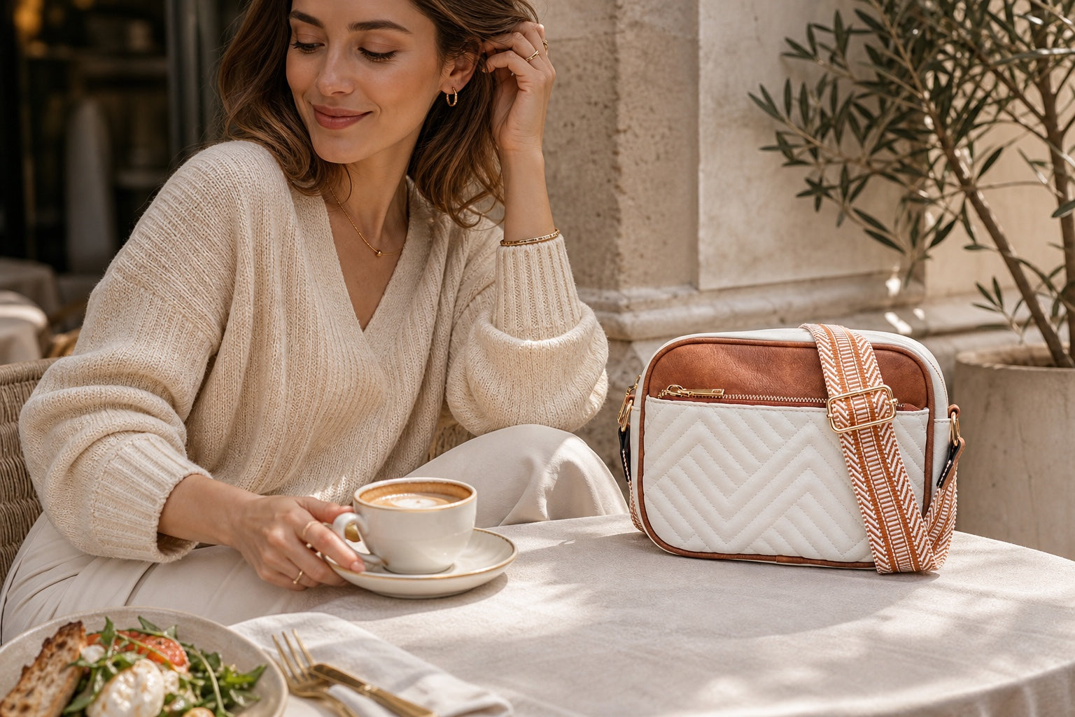 Woman styling the Noa ivory crossbody at a European café